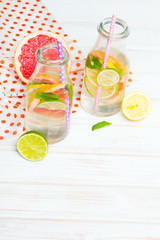 Infused flavored water with fresh fruits on white wooden background.Refreshing summer homemade  detox water