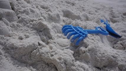 Fototapeta na wymiar blue kids rake on white sand