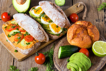 Sandwiches with avocado, eggs and tomato on a wooden background. Fresh organic vegetables, eggs and whole wheat bread. Healthy breakfast. Retro style.