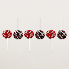 Lollipop Flat lay Minimal concept Six colored Lollipops are lying in a row on white background Classic round red-white and brown-white candy on a stick Trendy photo template for banner, poster, web
