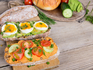 Sandwiches with avocado, eggs and tomato on a wooden background. Fresh organic vegetables, eggs and whole wheat bread. Healthy breakfast. Retro style.