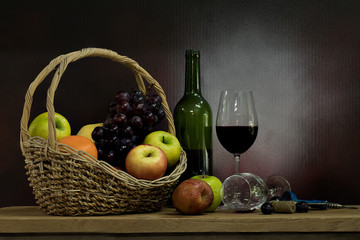Grape wine and fruit basket on wooden table on dark background.Still life style and selective focus.