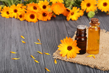 aromatherapy essential oil with fresh marigold flowers on old wooden background. Calendula oil