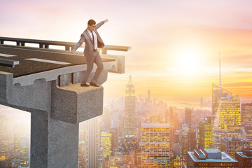 Businessman in uncertainty concept with broken bridge