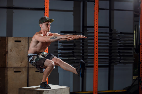 Brutal tattooed calisthenics coach shows exercise moves one leg squat