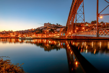 Iconic symbol of Oporto city. Bottom view of scenic iron arch bridge Dom Luis I reflecting on Douro River at twilight in Porto, Portugal's second largest city. icturesque urban evening skyline.