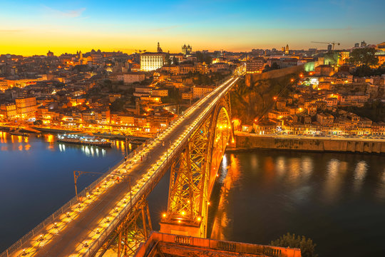 Panoramic aerial view of iron arch bridge Dom Luis I on Douro River at sunset twilight in Porto, Portugal's second largest city. Urban night skyline. Iconic symbol of Oporto city.