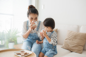 Happy family of asian mom is drinking milk with her cute daughter in the morning at home