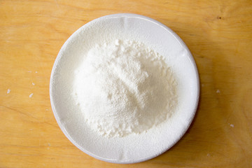 Plate with flour on a wooden table