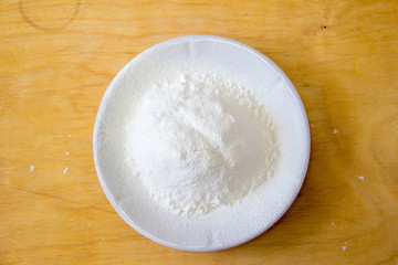 Fototapeta na wymiar Plate with flour on a wooden table