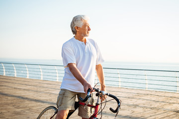 Portrait of handsome senior man riding bike on seafront