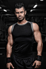 Fototapeta na wymiar Portrait of sporty healthy strong muscle charismatic handsome man bodybuilder in black t-shirt and shorts outfit with brutal serious look and nice modern hairstyle