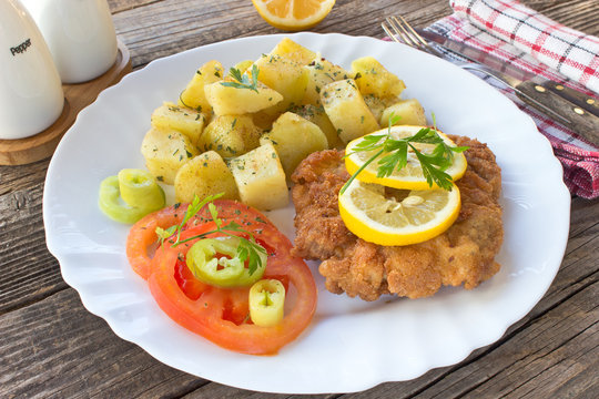 Wiener schnitzel with potatoes in plate on table