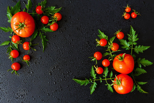 Fresh juicy tomatoes, cherry and leaves pattern and ornament on a dark background with copy space flat view from above