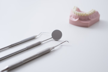 Close up of dental tools and instruments and plastic mouth model on white background