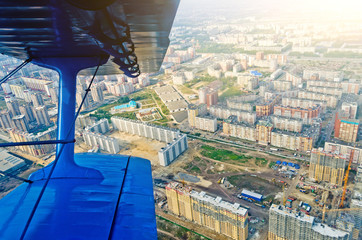 View in the porthole airplane of a turboprop aircraft biplane on the city streets and houses.