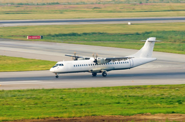 A turboprop passenger plane lands on the runway at the airport, the reverse.