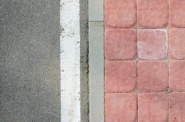 Texture of the Asphalt Road Junction to the Sidewalk of the Red Concrete Paving Stone