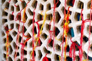 Marble mesh covered with sacred multicolored threads. These threads are tied to the mosque by...