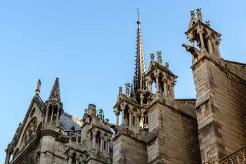 Close-up view from below of the spire of Notre-Dame de Paris cathedral with buttresses, pinnacles...