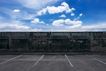 Empty parking lot and old gray block wall with the blue sky and cloud.