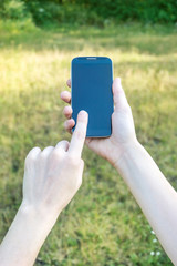 A woman's hands using a smartphone outdoors.