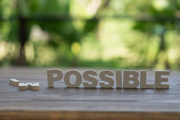 The letters word IMPOSSIBLE in motivation meaning of impossible make it possible concept. On wood background.