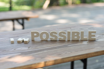 The letters word IMPOSSIBLE in motivation meaning of impossible make it possible concept. On wood...