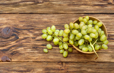 Bowl with fresh ripe green grapes on wooden background. Top view.