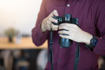 Man holding camera Wearing a red and black plaid. 