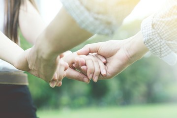 Close up of loving couple holding hands while walking at parks.