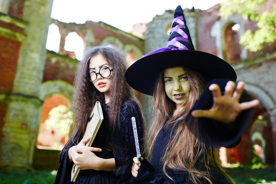 Little black witch and her friend in halloween costumes