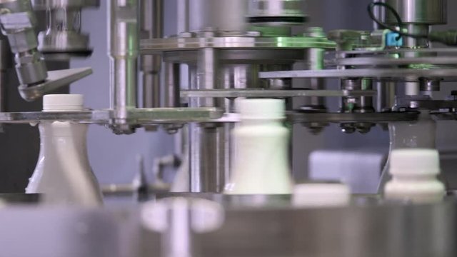A moving shot of a milk production line, the bottles are filled with milk and then hermetically sealed
