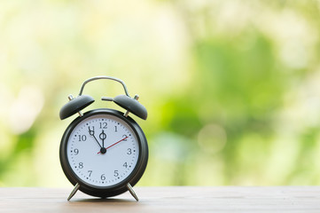 Retro alarm clock with five minutes to twelve o'clock.