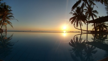 Sunset with beautiful reflection at the infinity pool by the sea