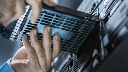 Low Angle Shot In Fully Working Data Center IT Engineer Installs Hard Drive into Server Rack....