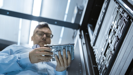 Low Angle Shot In Fully Working Data Center IT Engineer Installs Hard Drive into Server Rack. Detailed and Technically Accurate Footage.