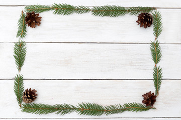 Frame in the shape of a rectangle of twigs of a Christmas tree on a wooden background. Flat lay