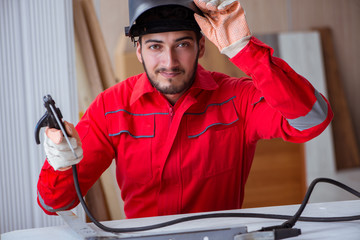 Young repairman with a welding gun electrode and a helmet weldin