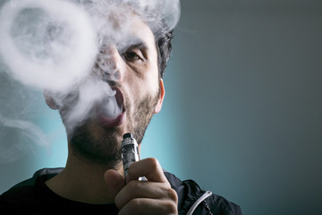 young man vape electronic cigarette cloud by using a mod, smoke tricks of vaping device background. 