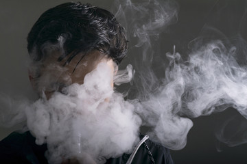 young man vape electronic cigarette cloud by using a mod, smoke tricks of vaping device background. 