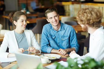 Young man and woman listening to applicant during interview in cafe