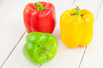 Red yellow and green fresh whole raw pepper on old white rustic planks