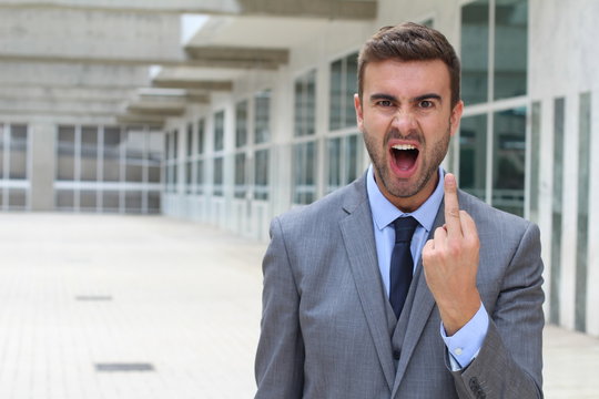 Moody businessman screaming and showing the middle finger