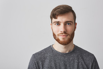 Close up portrait of beautiful manly bearded guy with stylish hairstyle smiling, looking in camera...