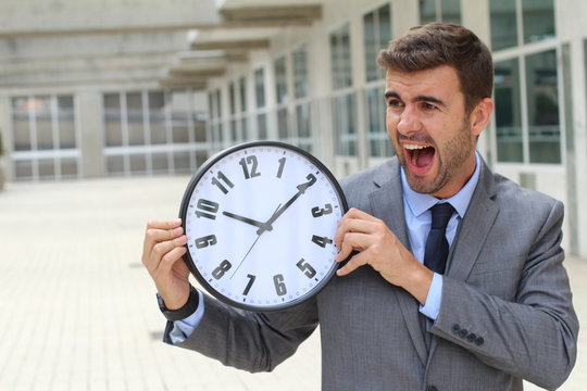 Businessman screaming while holding a big clock