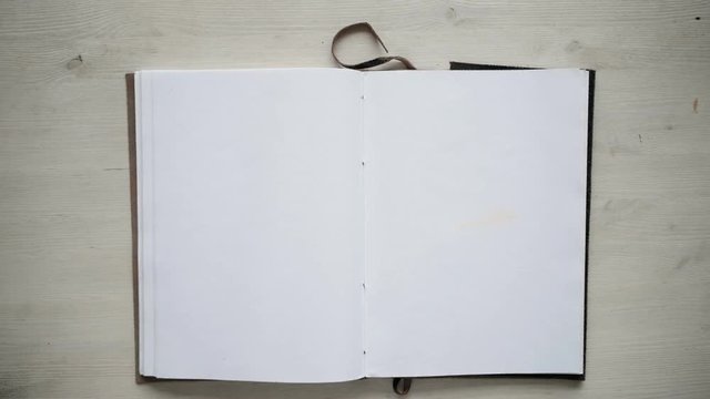 Top view on isolated artisan notebook on white table. Man's hand open it and leave alone. Education mockup concept