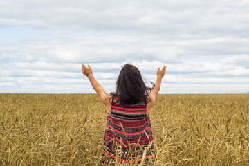 young brunette girl standing on wheat field and enjoying nature