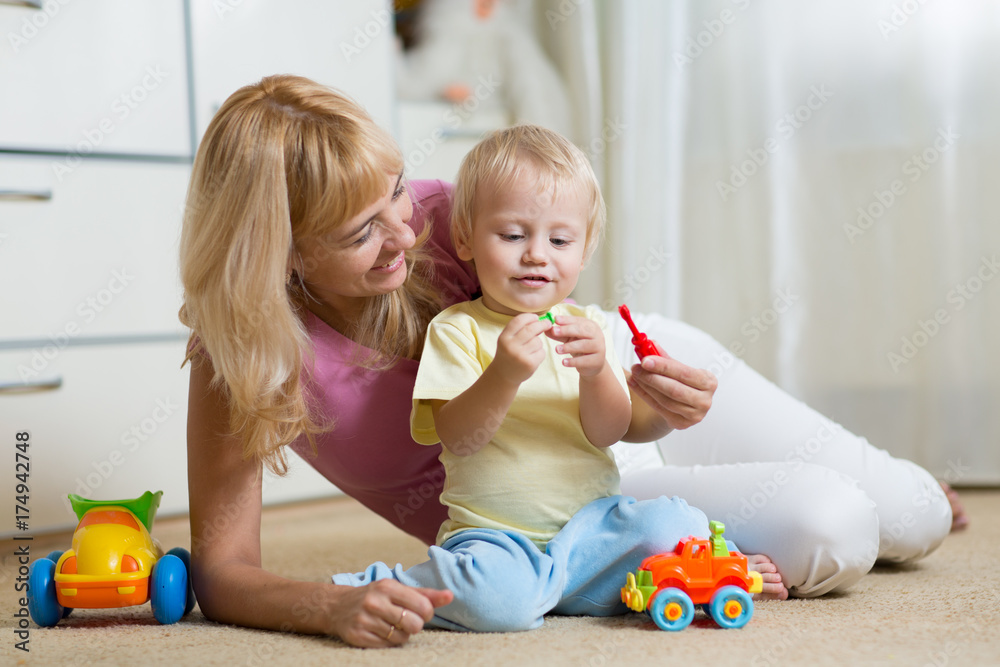 Wall mural cute mother and kid boy playing together indoors at home