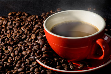 Hot coffee in red cup and coffee beans are the background.